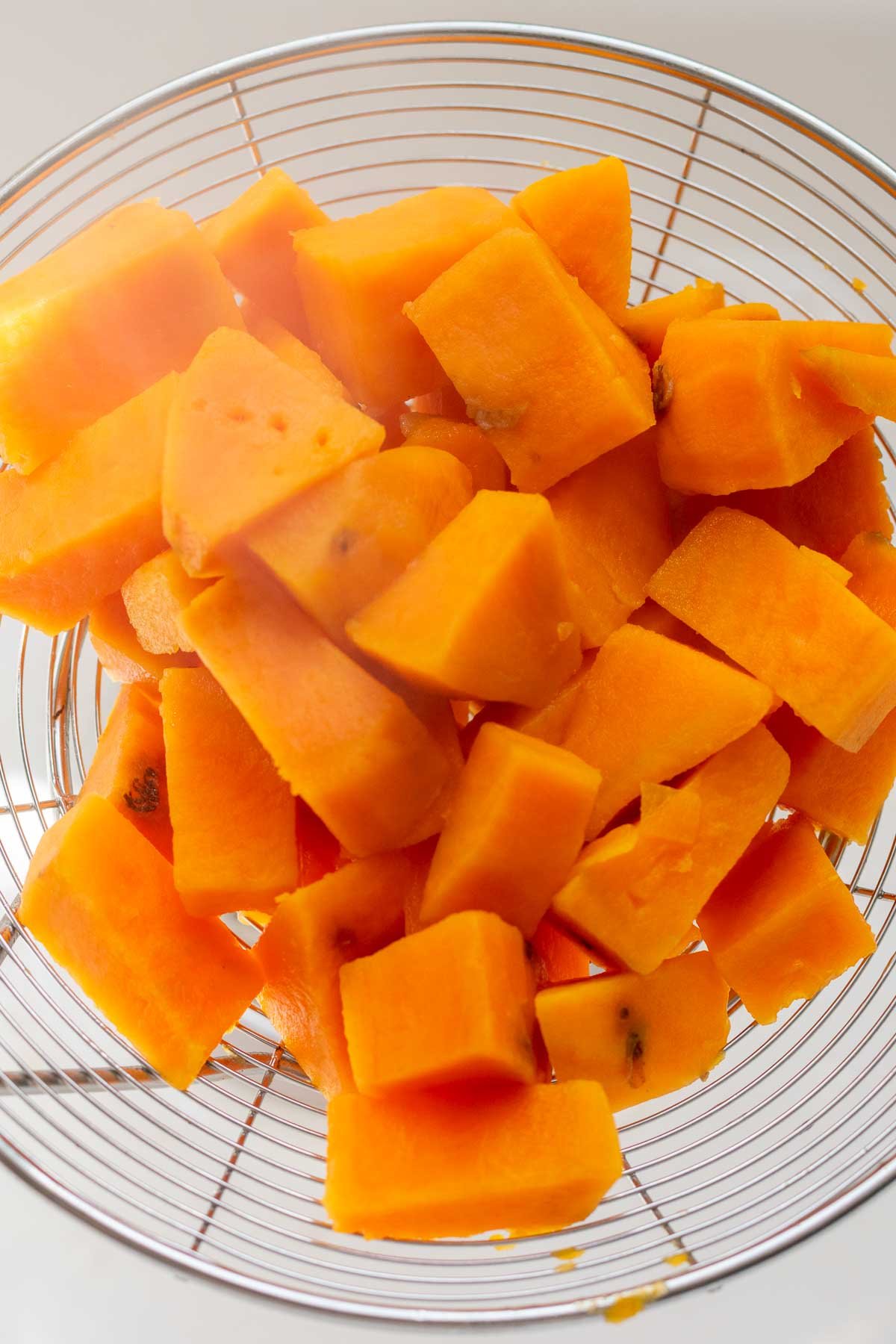 Cooked sweet potatoes in a strainer.