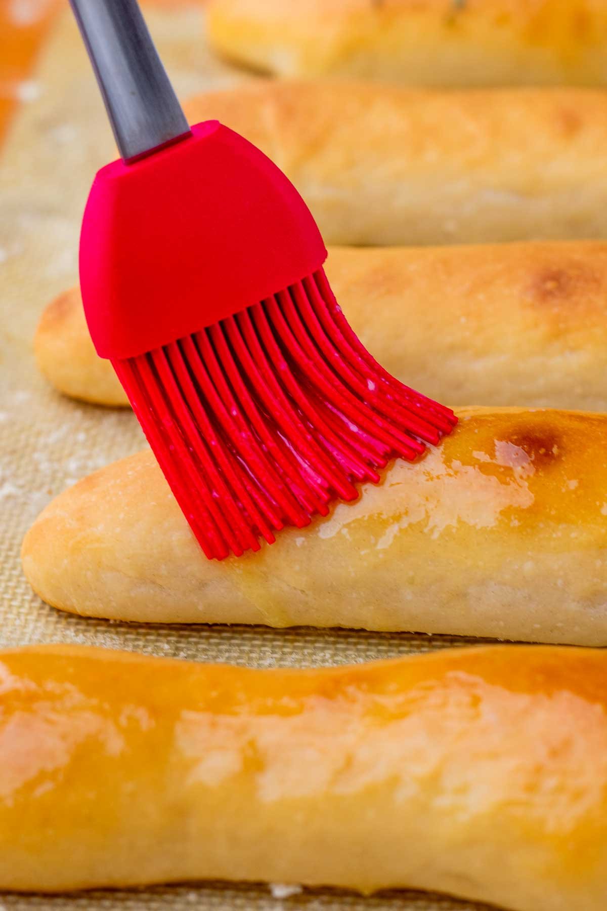 Brushing butter on sourdough breadsticks.