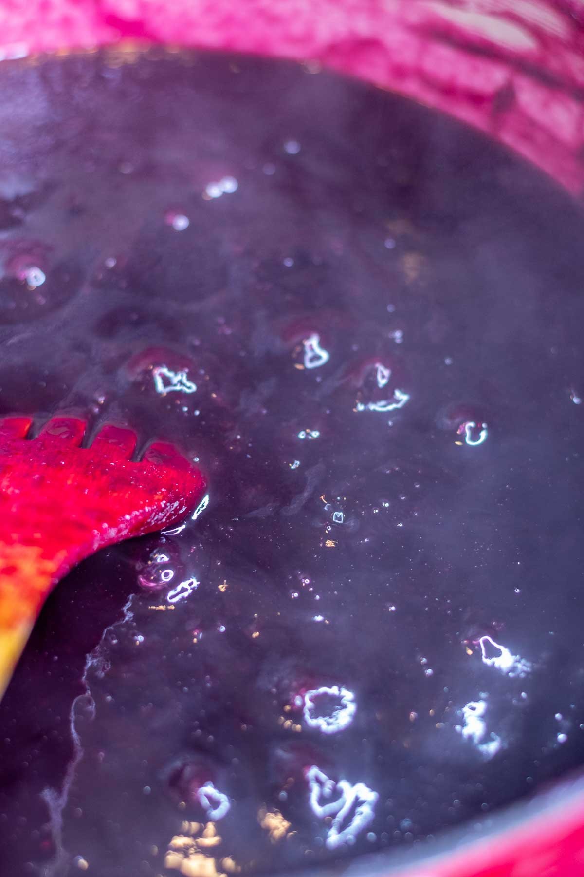 Concord grape jam in Dutch oven with large bubbles near end of cooking.