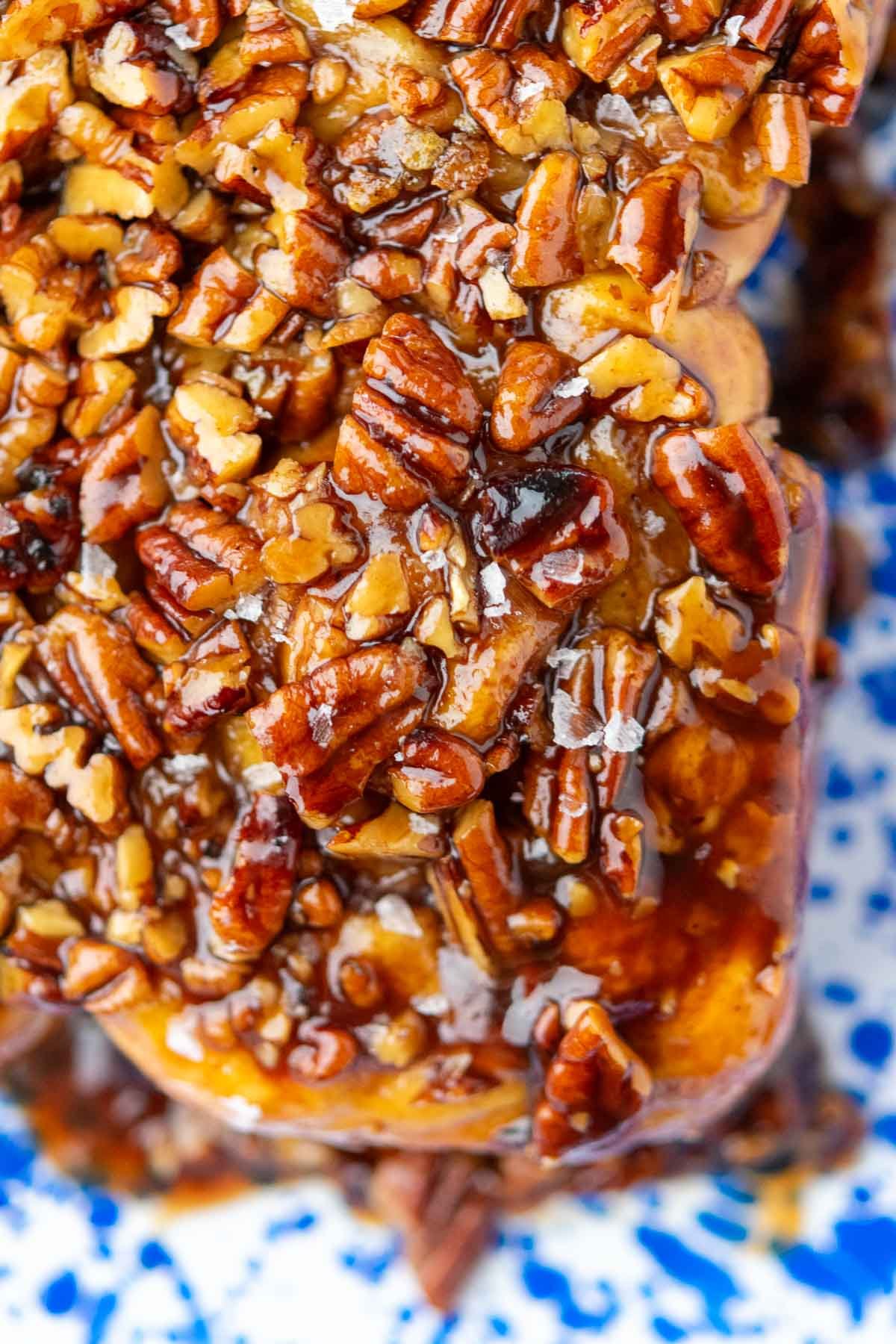 Close up of gooey sourdough sticky buns with maple pecan topping and flaky salt.
