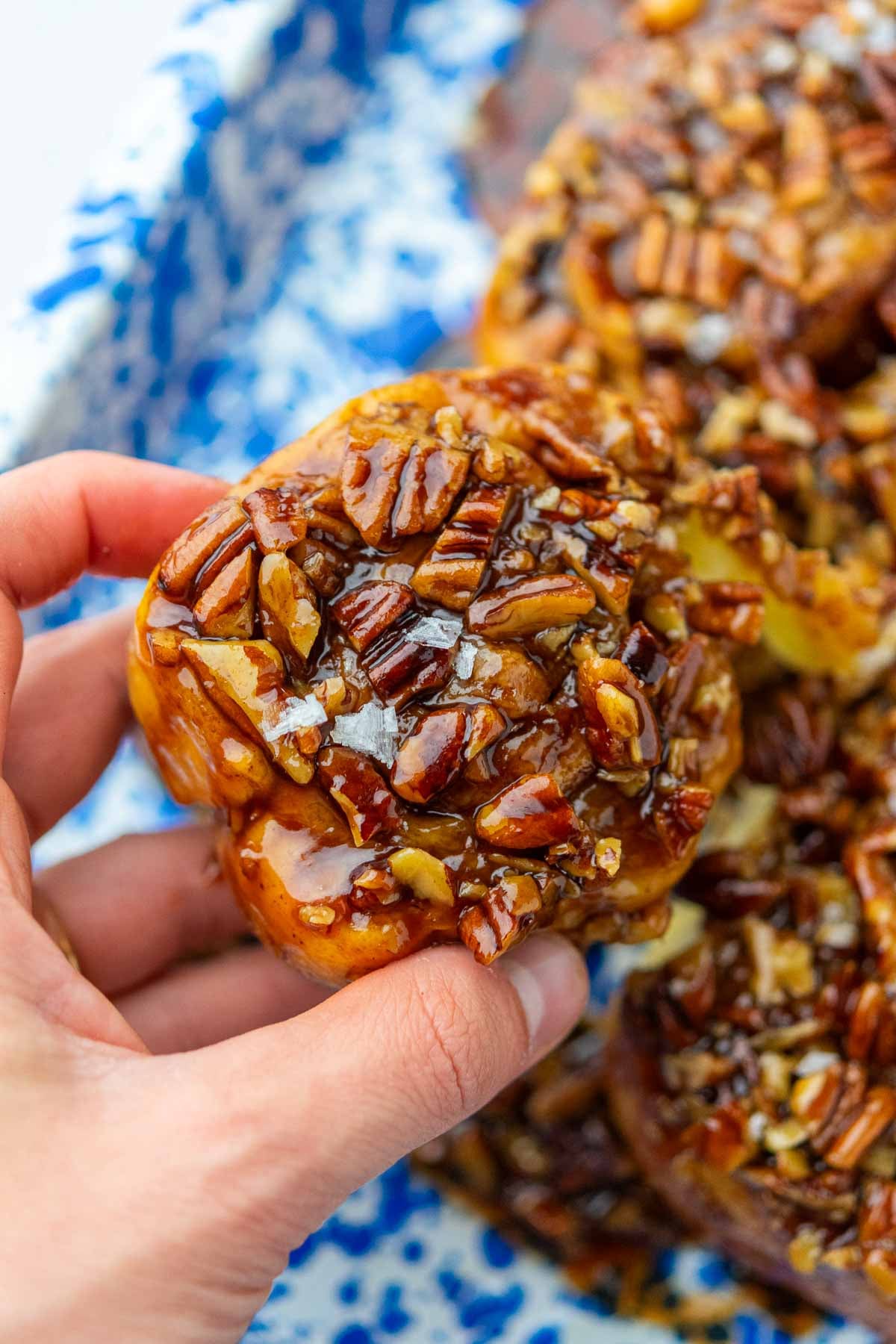 Hand holding a sourdough maple pecan sticky bun.