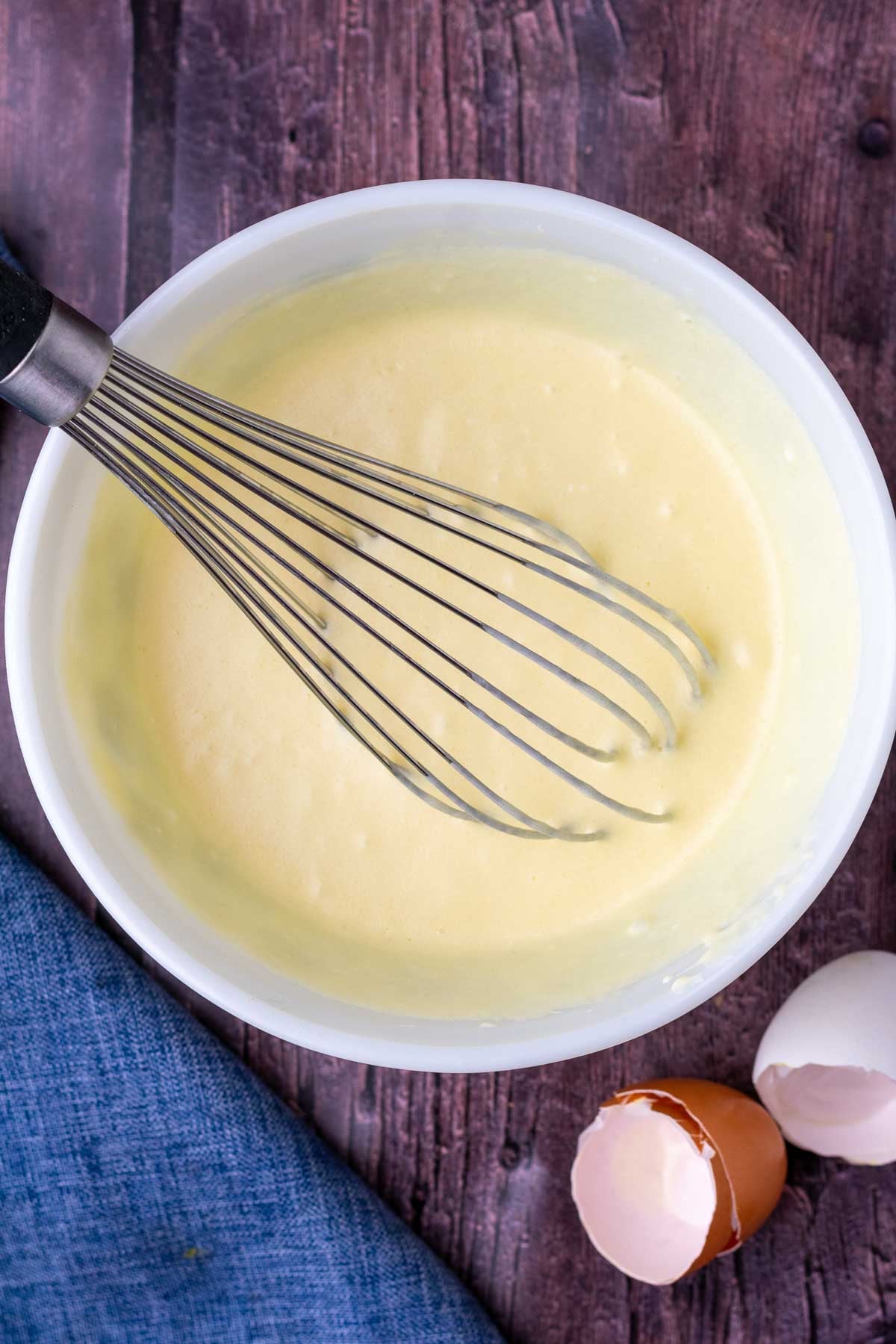 Mixed wet ingredients for sourdough cranberry muffins in a bowl with a whisk.