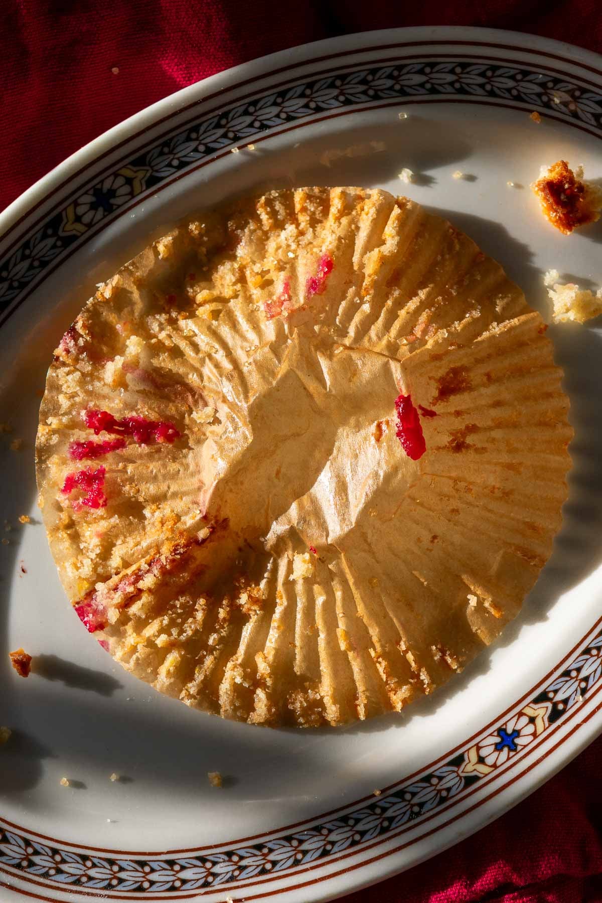 Paper muffin liner on plate from eaten a sourdough cranberry muffin.