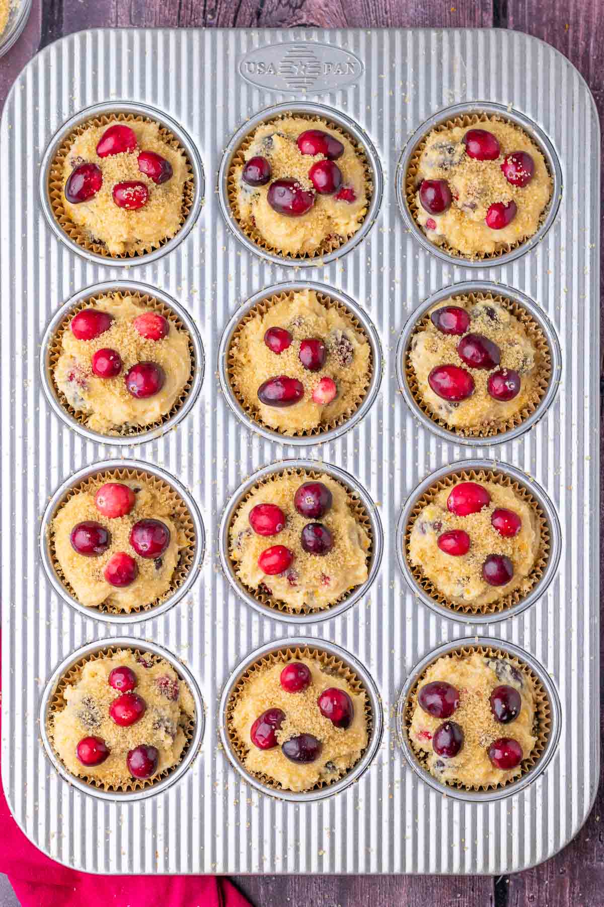 Muffin pan with unbaked sourdough cranberry muffins.