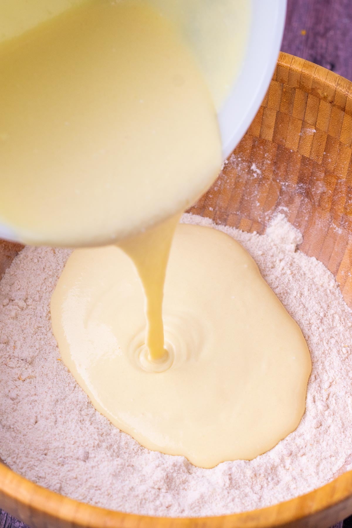 Pouring wet ingredients into dry ingredients for sourdough cranberry muffins.