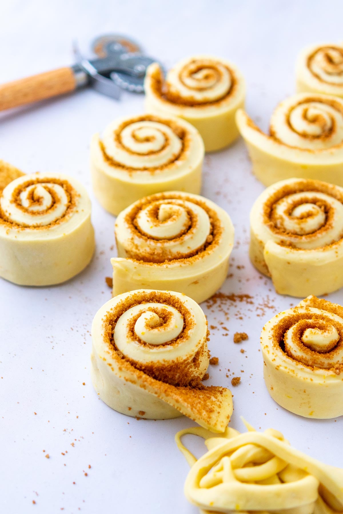 Sliced sourdough sticky buns on a work surface with a pastry wheel.