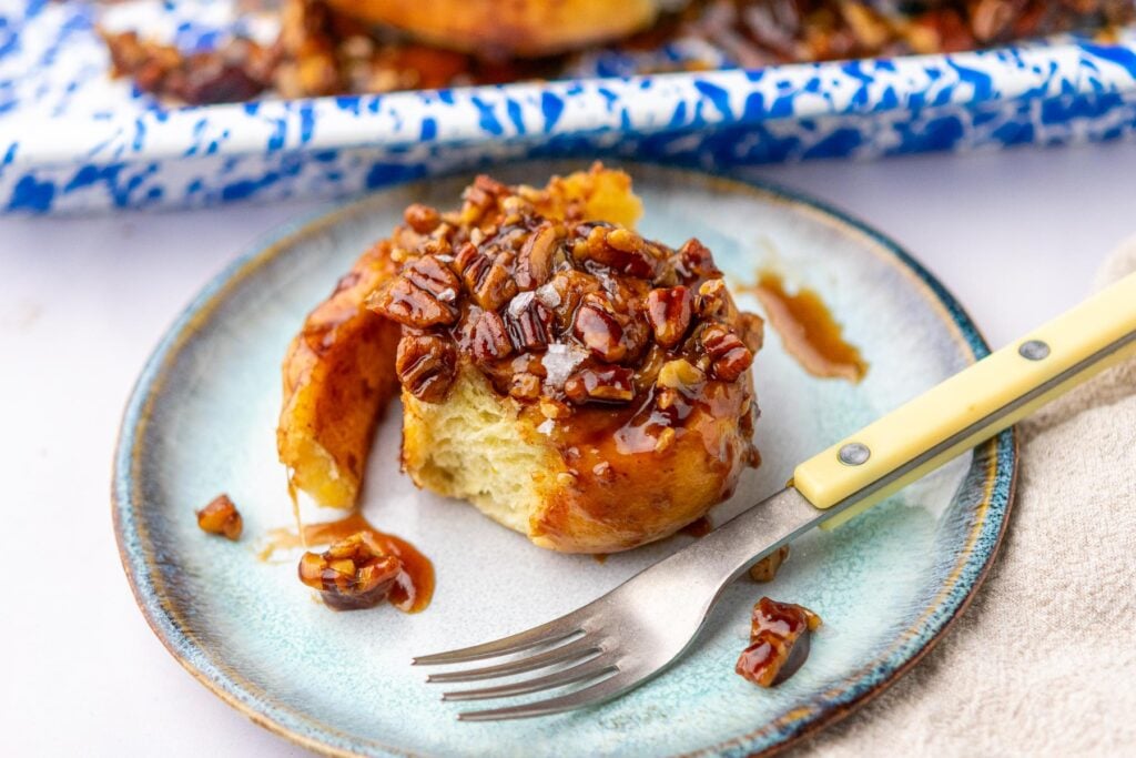 Sourdough maple pecan sticky bun on a plate with a fork.