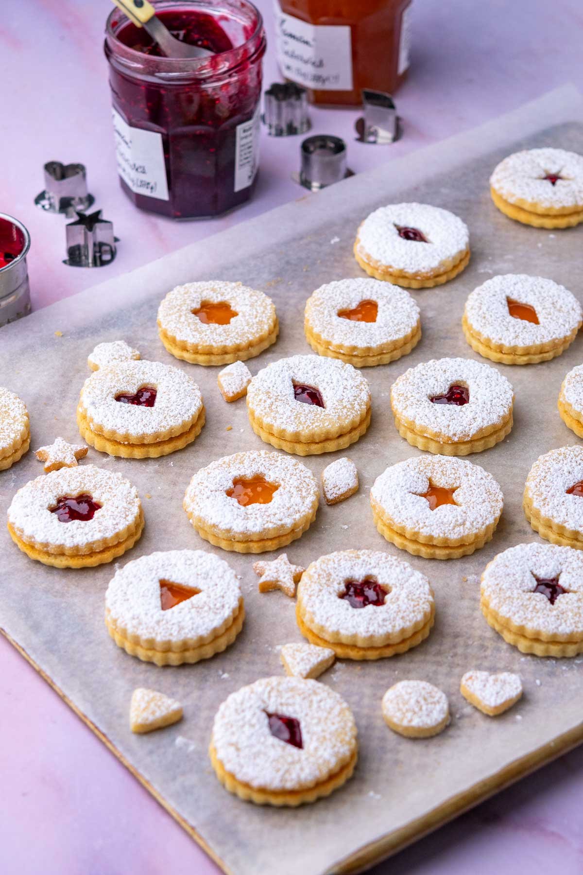 Baking sheet with assembled sourdough linzer cookies and jam.
