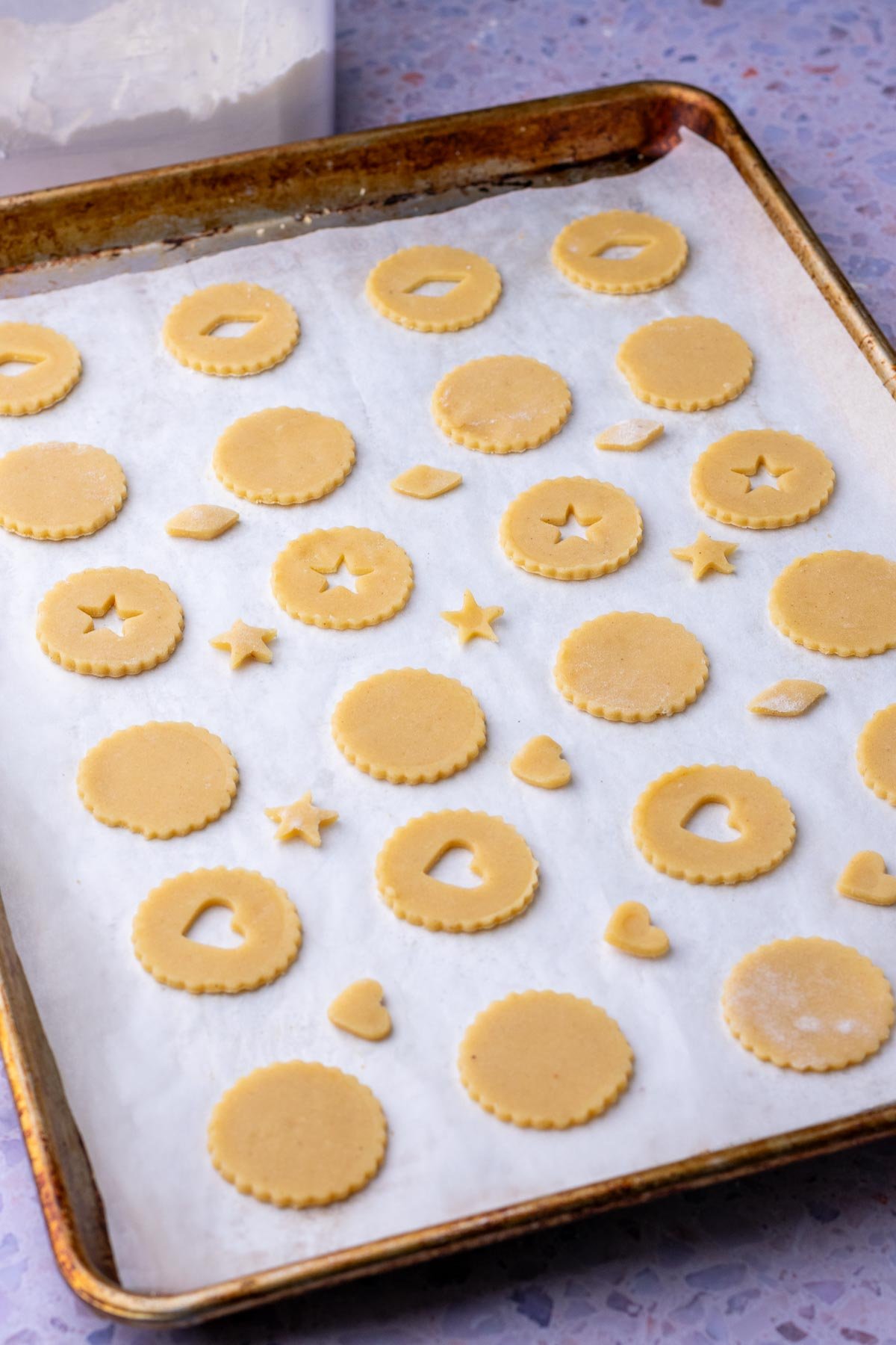 Baking sheet with unbaked sourdough linzer cookies with various shapes.