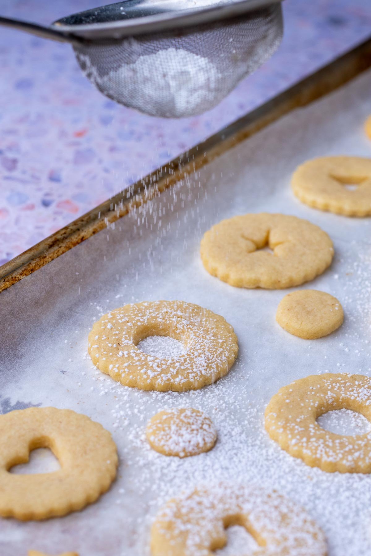 Dusting powdered sugar on sourdough linzer cookies.