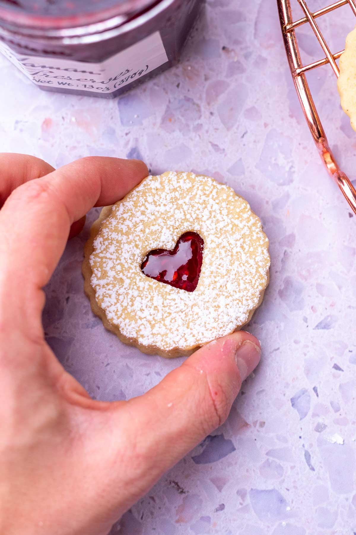 Hand assembling and sandwiching a sourdough linzer cookie with a heart.