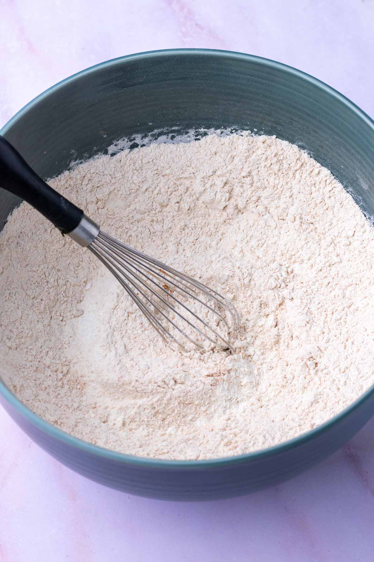 Bowl of dry ingredients for Sourdough ginger molasses cookies with a whisk.