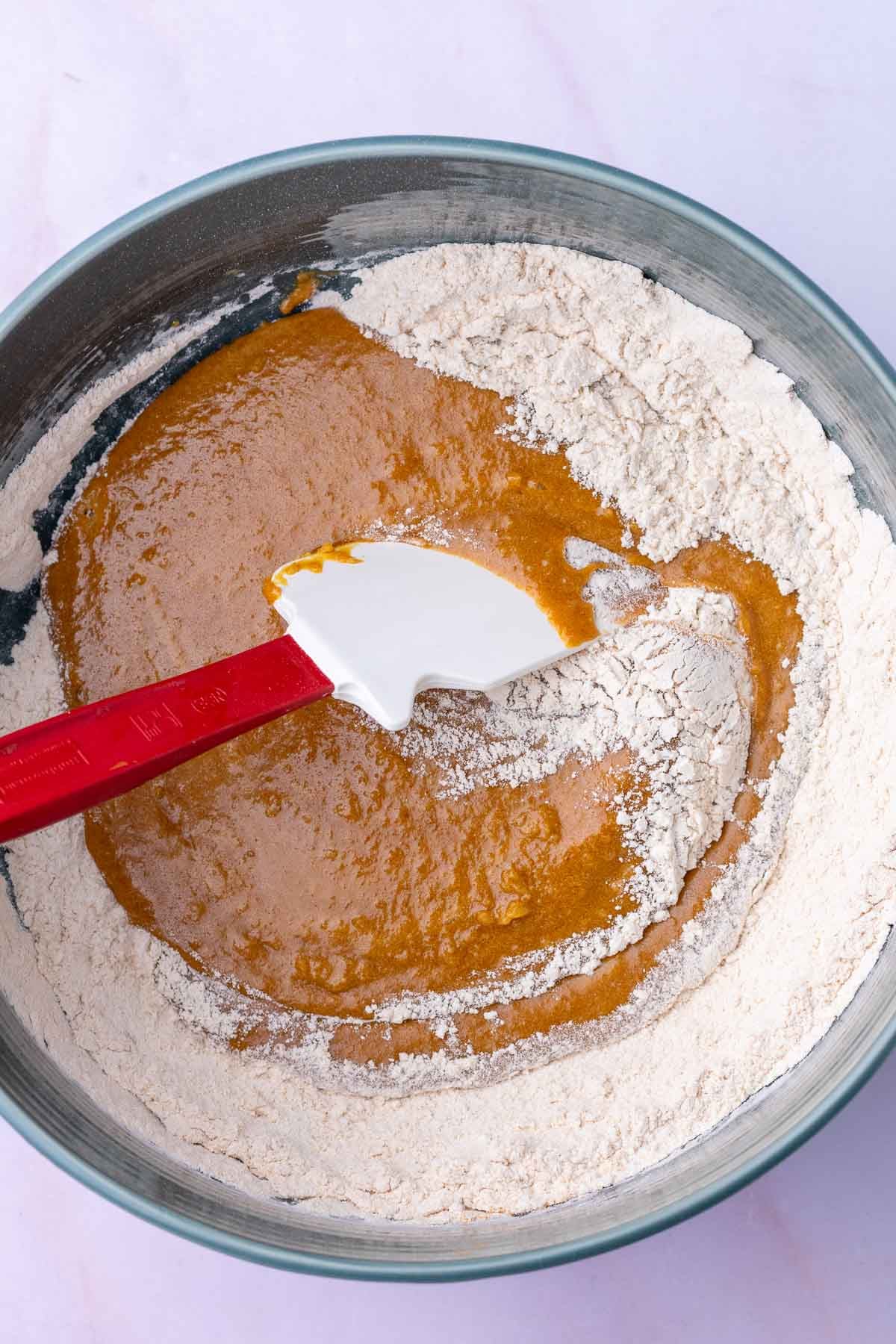Mixing Sourdough ginger molasses cookie dough in bowl with a spatula.