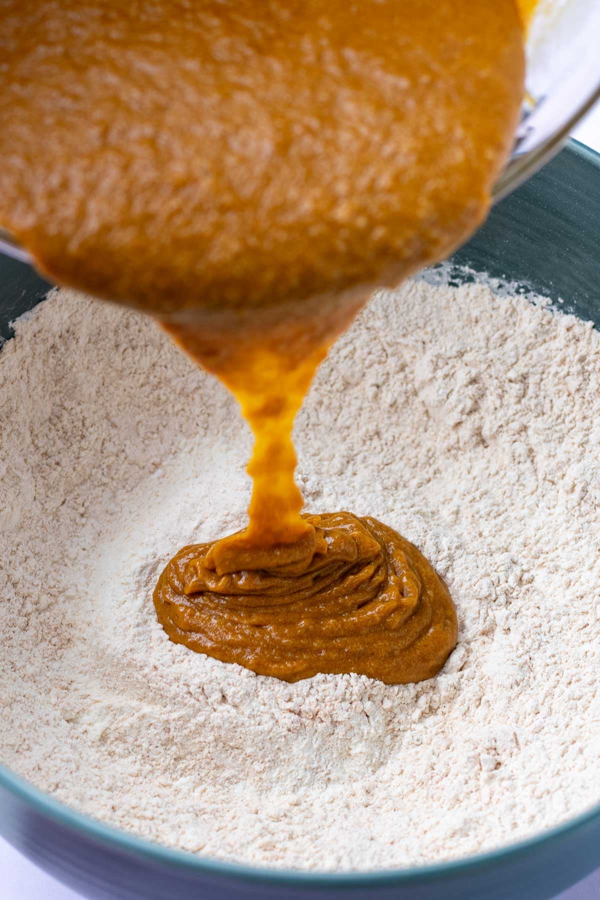 Pouring wet ingredients for Sourdough ginger molasses cookies into bowl of dry ingredients.