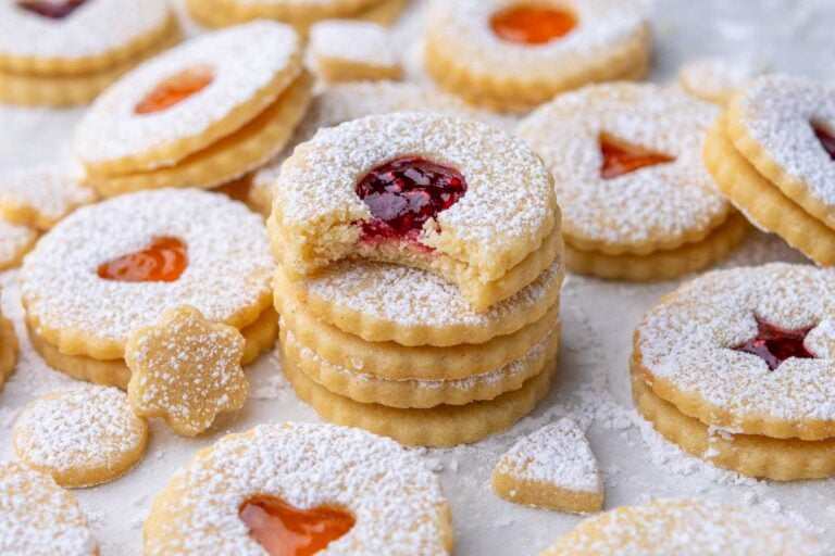 Many Sourdough Linzer Cookies with raspberry and apricot jam and dusted with powdered sugar.