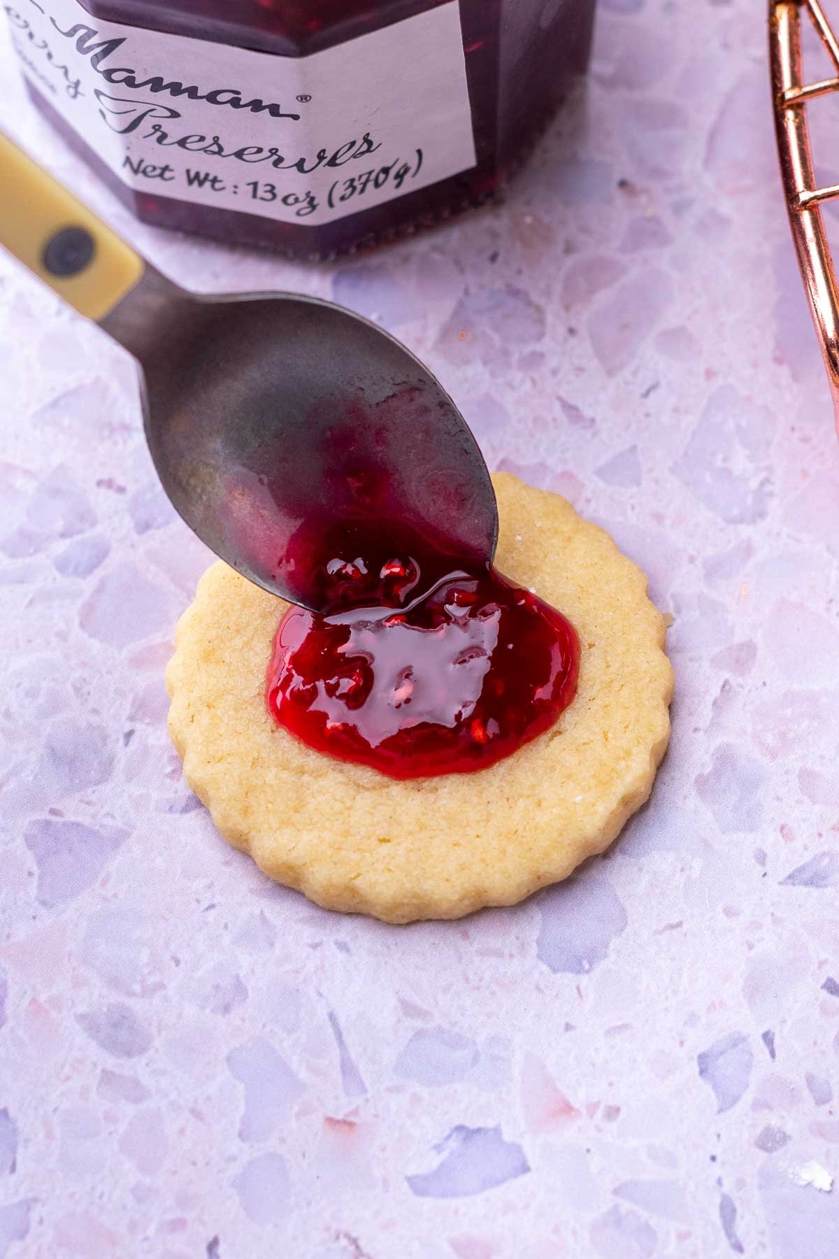 Spooning jam onto a sourdough shortbread cookie.