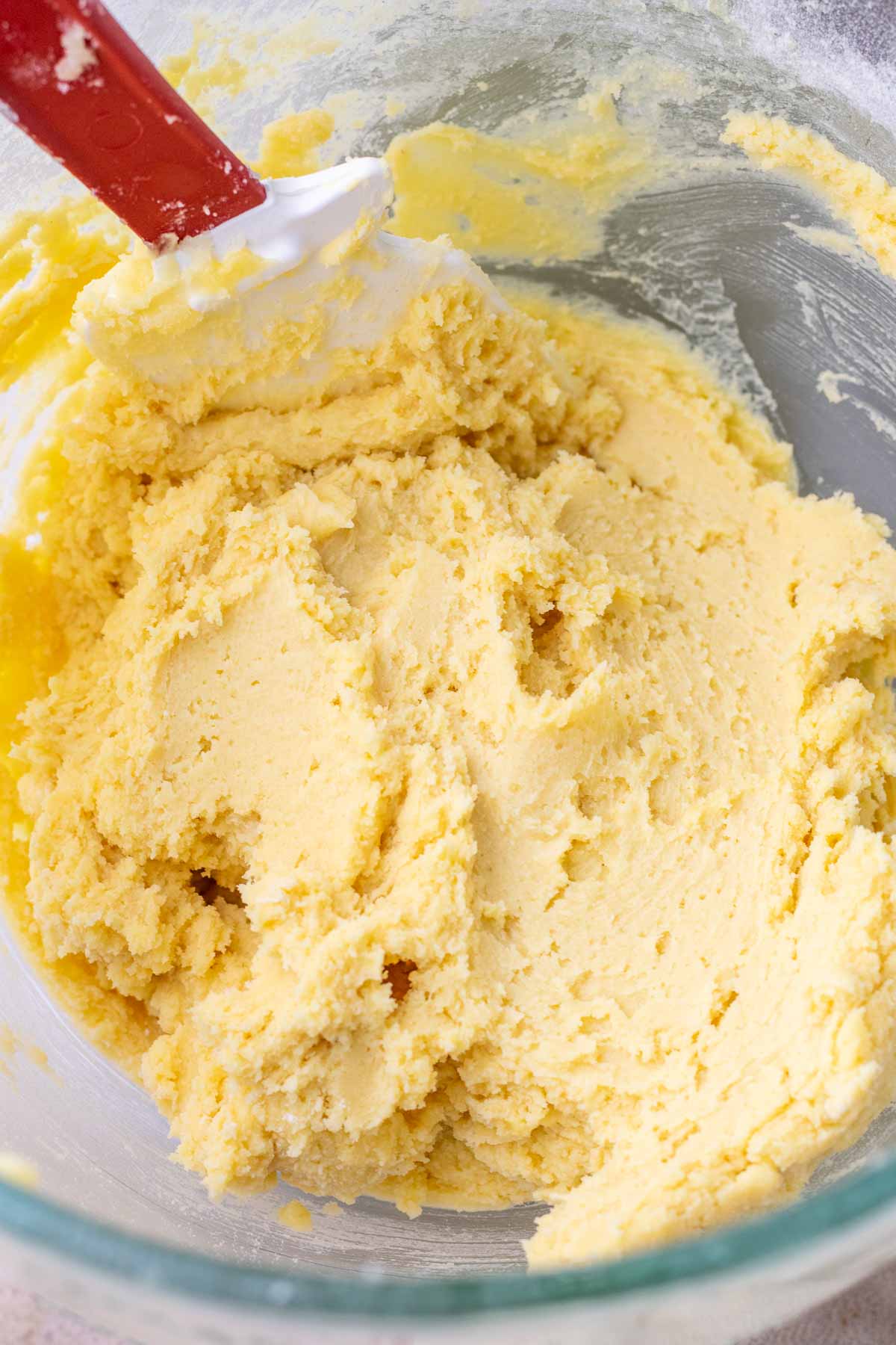 A bowl with mixed sourdough sugar cookie dough and a spatula.