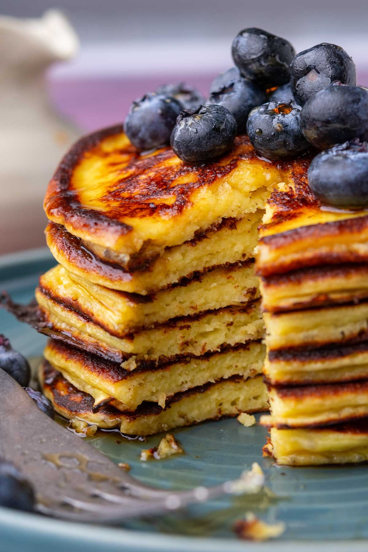 Stack of sourdough cottage cheese protein pancakes with a bite taken out and topped with blueberries.