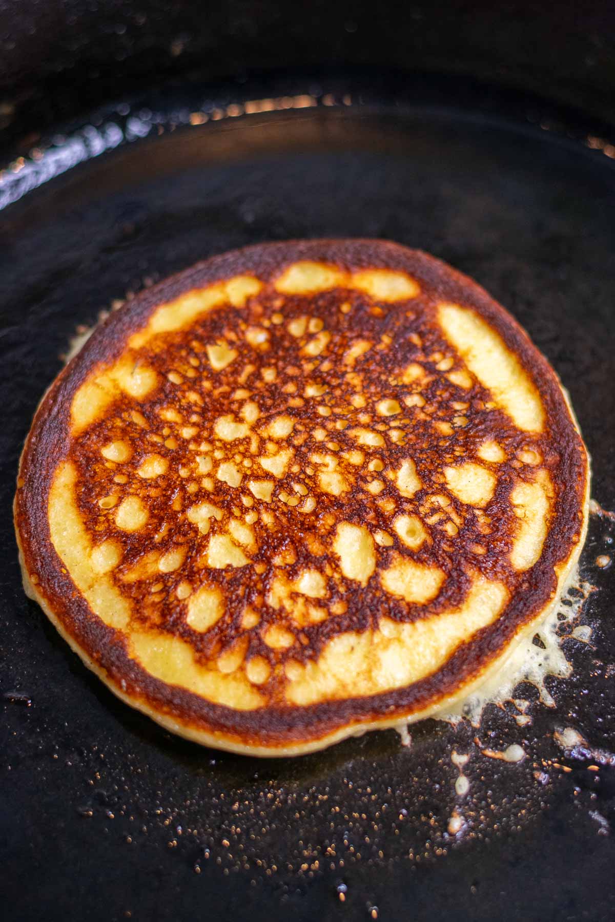 Flipped sourdough cottage cheese protein pancake in cast iron skillet.