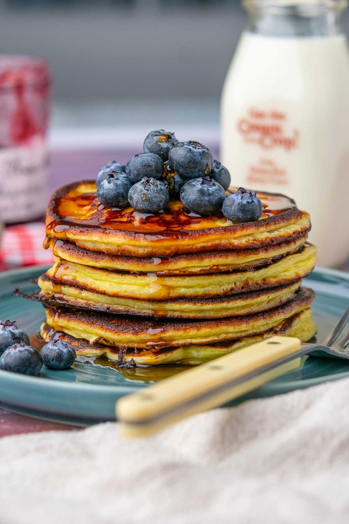 Stack of sourdough cottage cheese protein pancakes with blueberries and maple syrup.