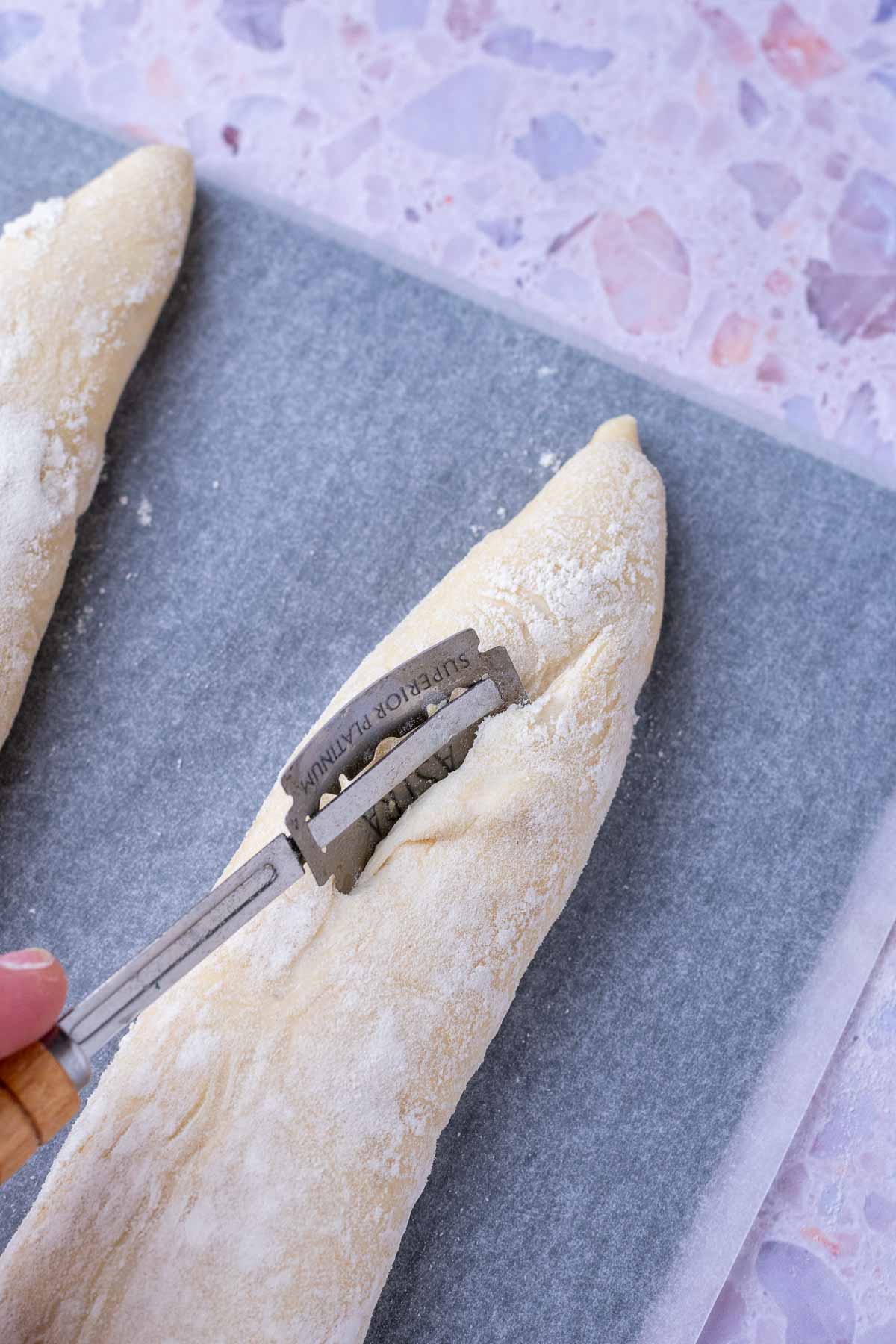 Scoring sourdough baguettes with a bread lame.