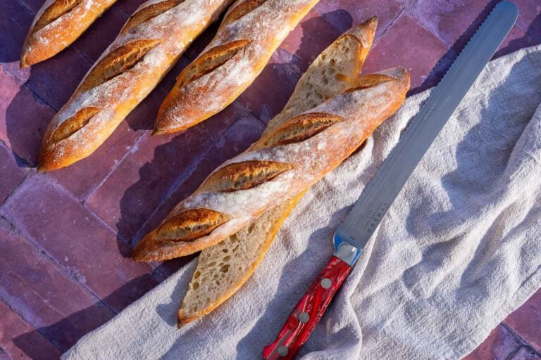 Sourdough baguettes with a bread knife and towel.