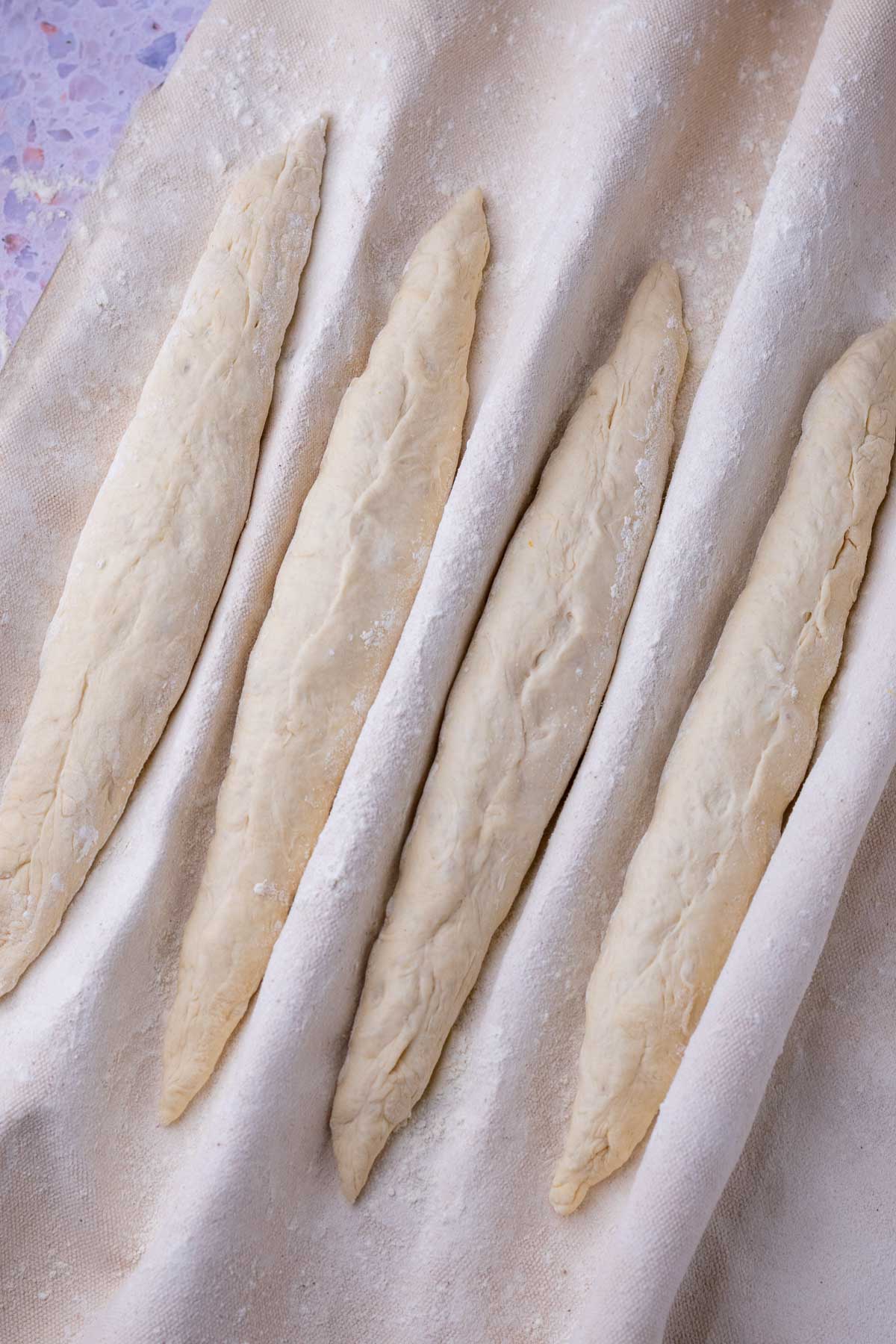 four sourdough baguettes in couche at the start of final proofing