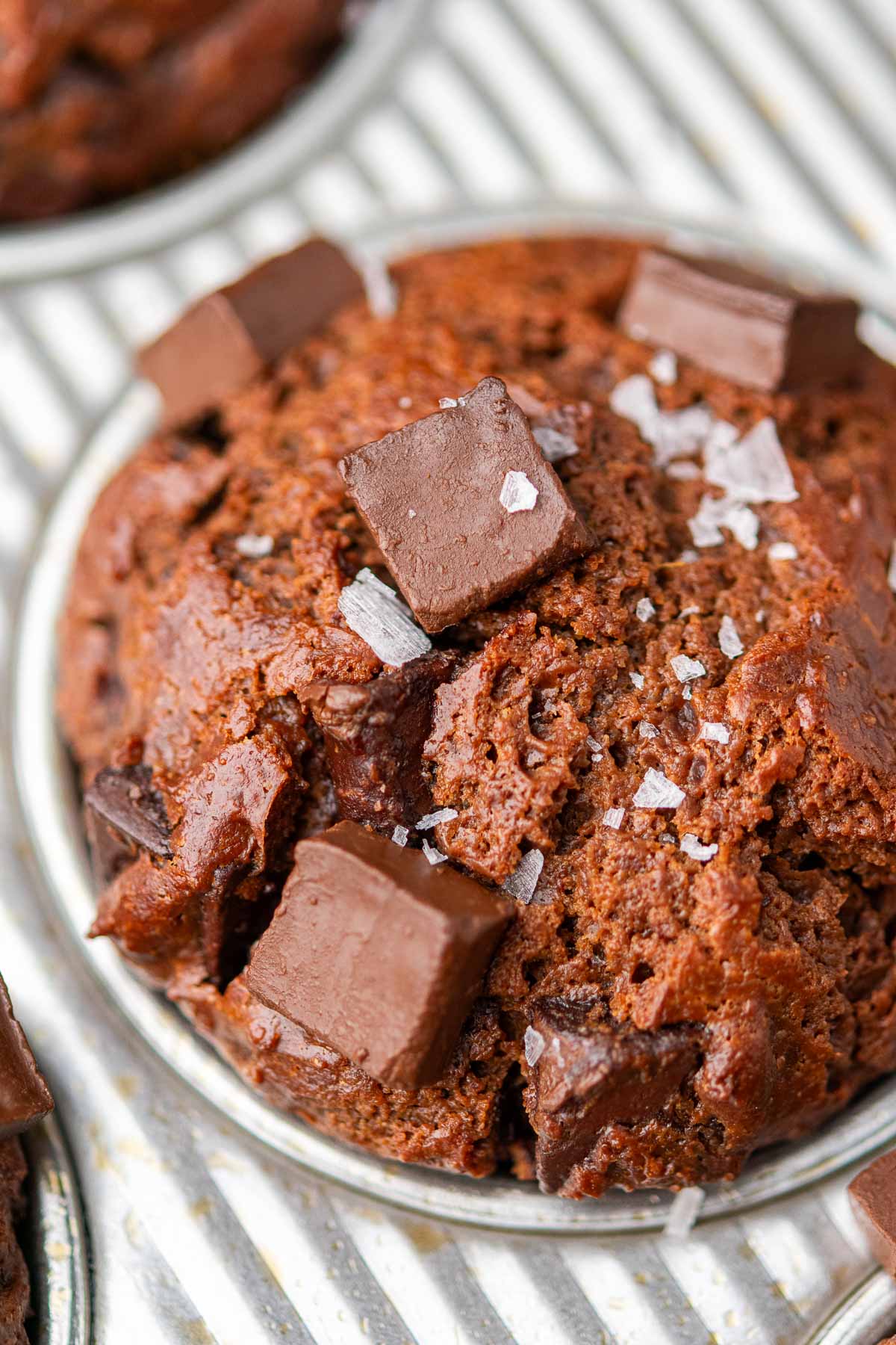 Close up of a baked sourdough discard chocolate muffin with chocolate chips and flaky salt.