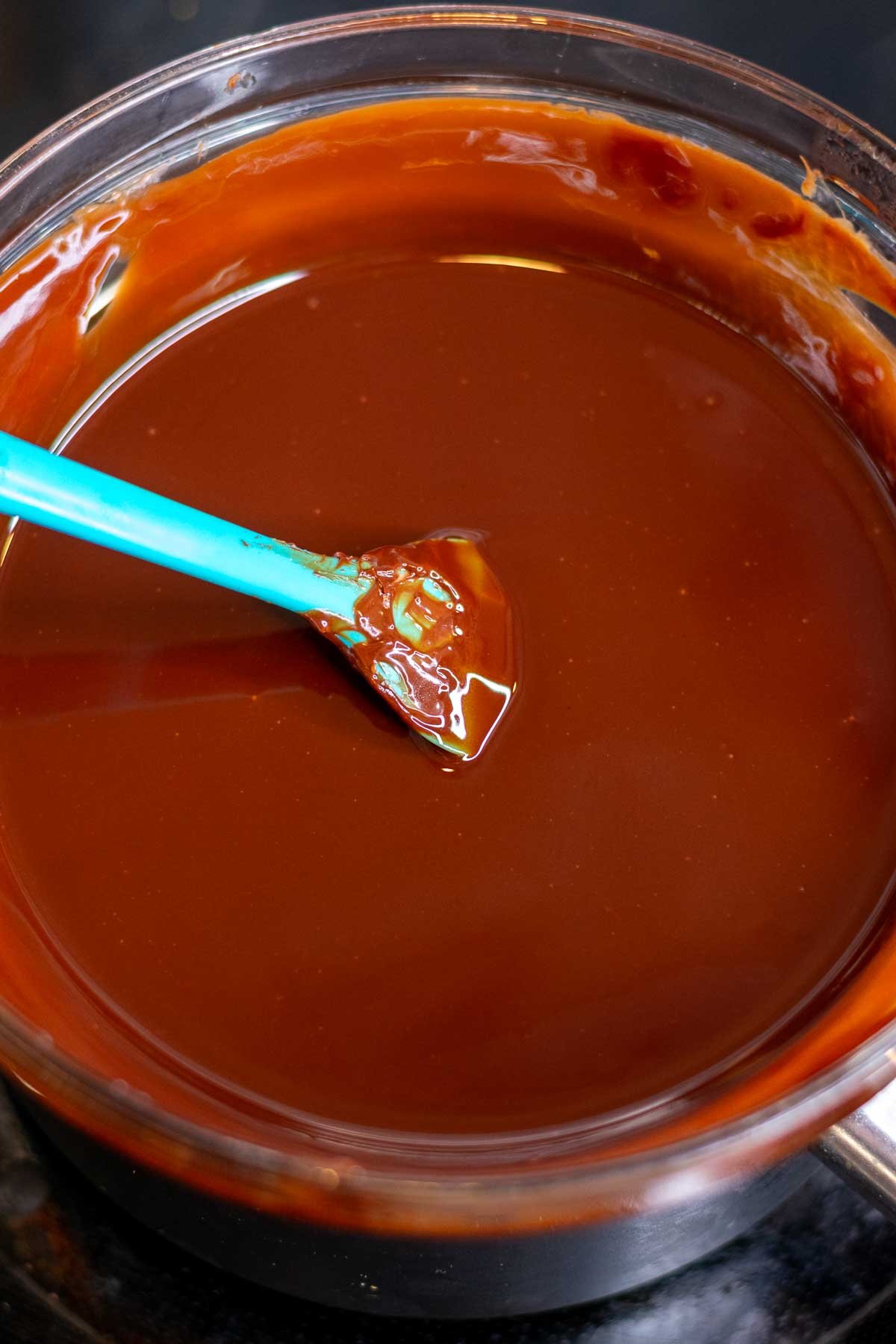 Melted chocolate chips and butter in a bowl with a spatula.