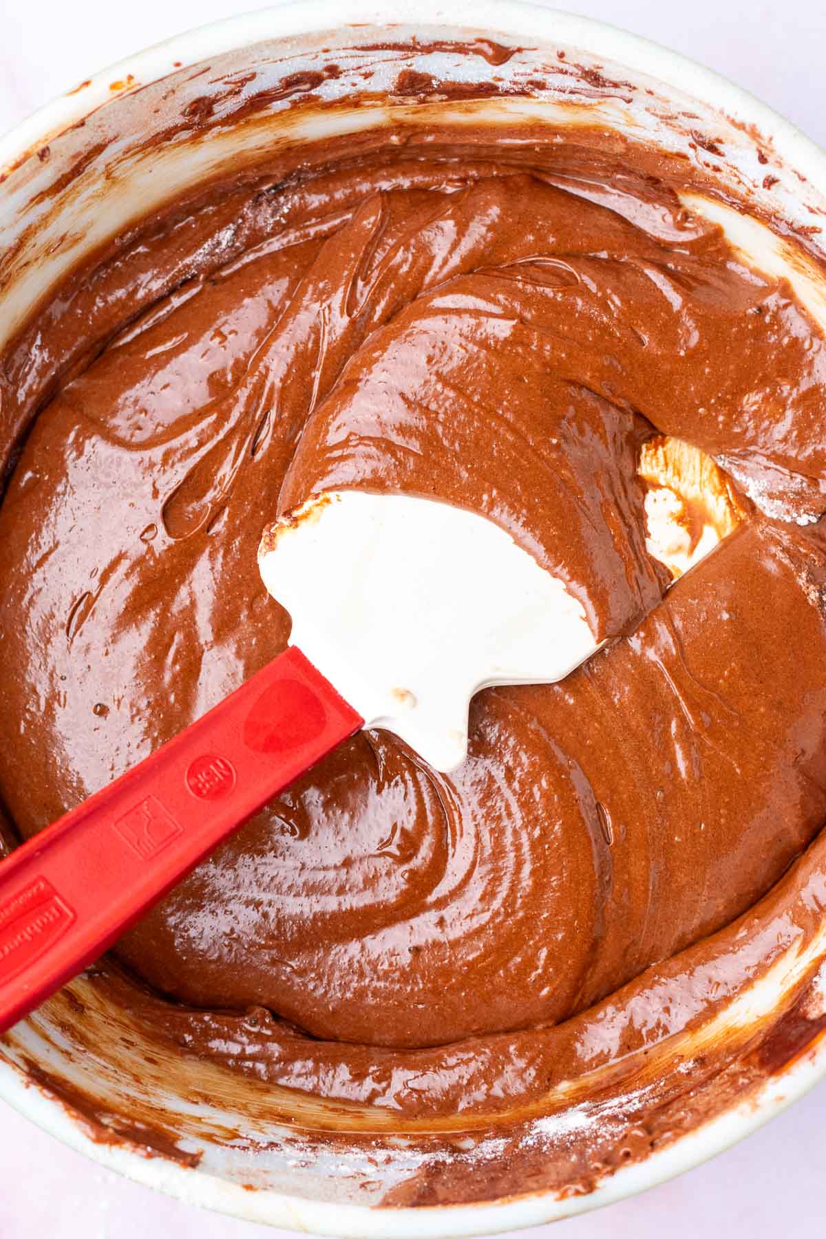 Folding sourdough brownie batter in a bowl with a spatula.