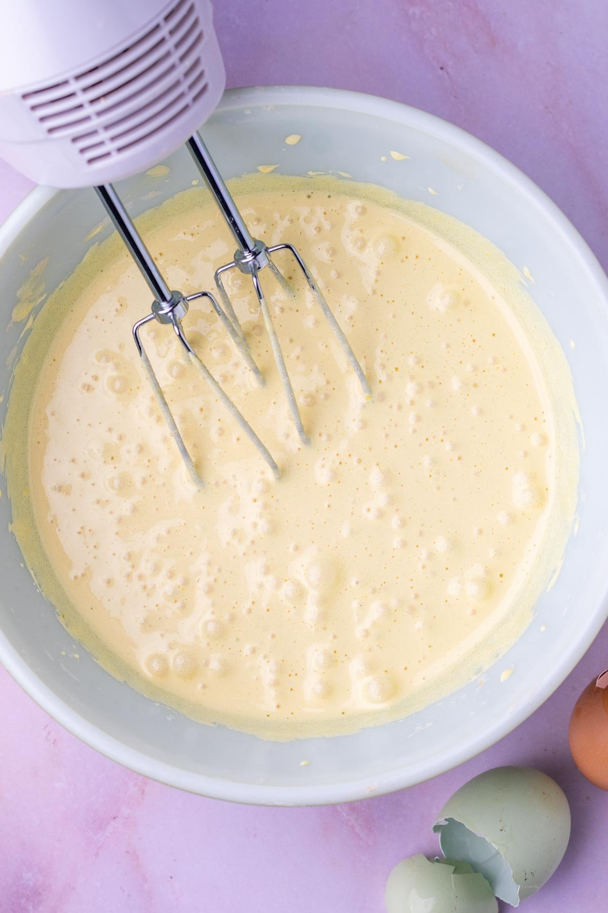 Whisking eggs and sugar in a mixing bowls with an electric hand mixer