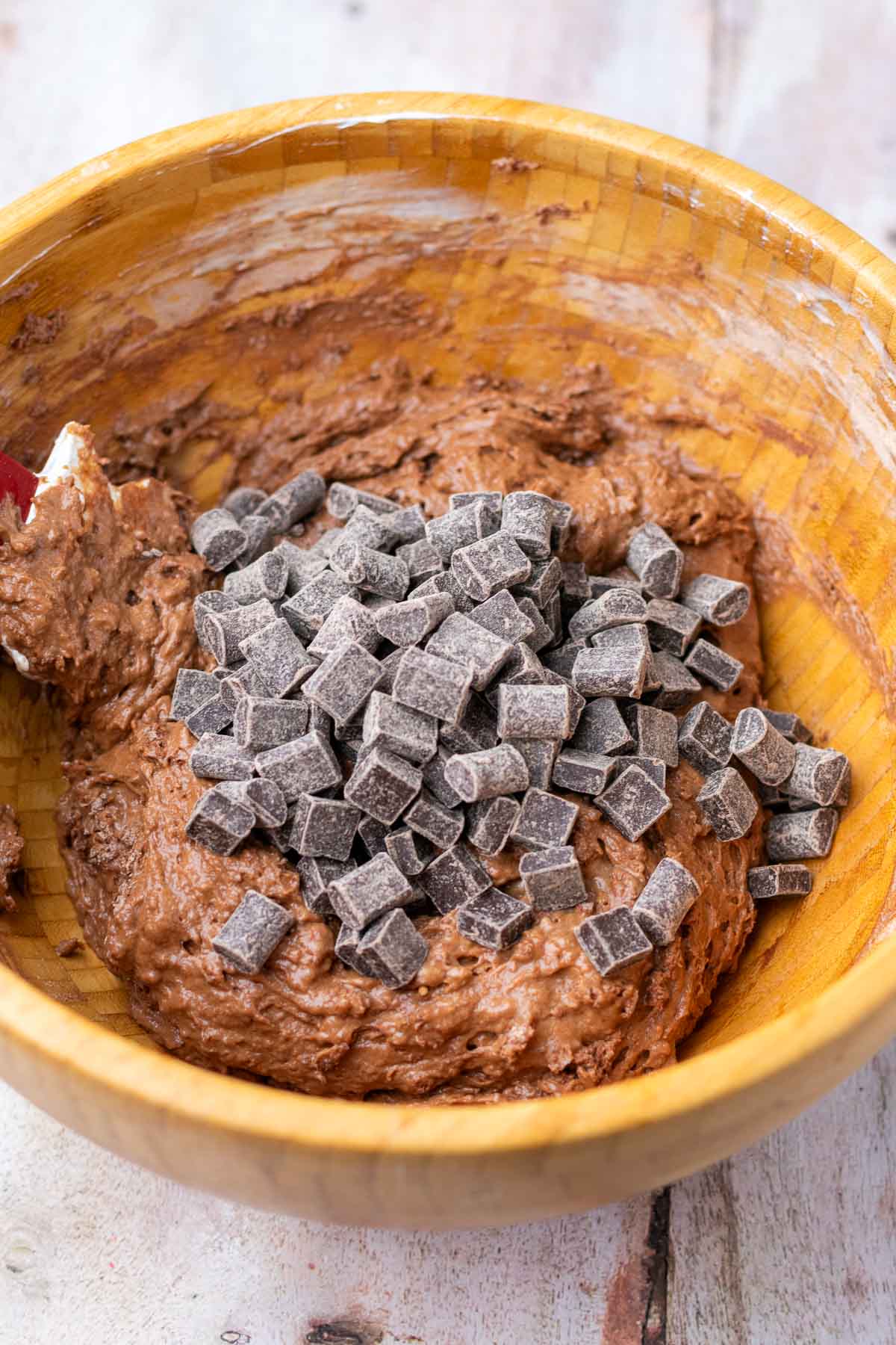 Chocolate chunks added to sourdough discard chocolate muffin batter in a bowl.