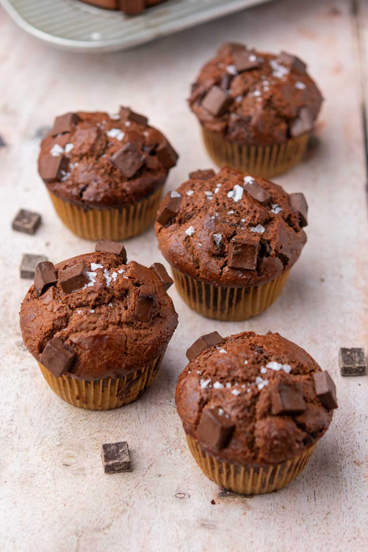 Multiple sourdough discard chocolate muffins with chocolate chunks and flaky salt.