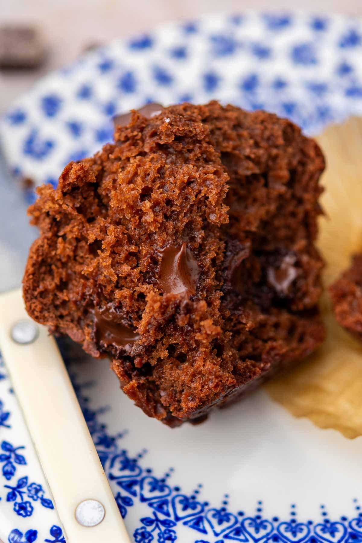 Gooey chocolate interior of a sliced sourdough chocolate muffin on a plate with a knife.