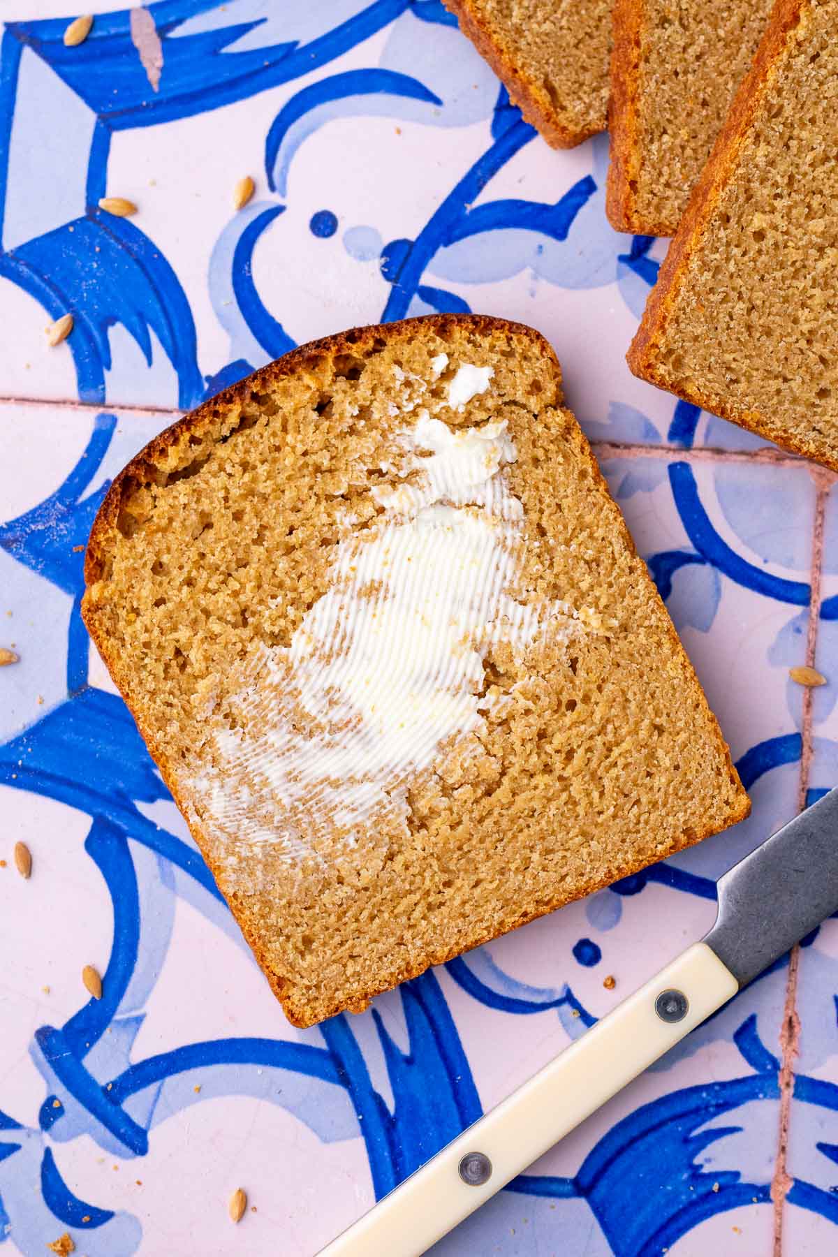 Slice of einkorn sourdough sandwich bread with butter and a knife.