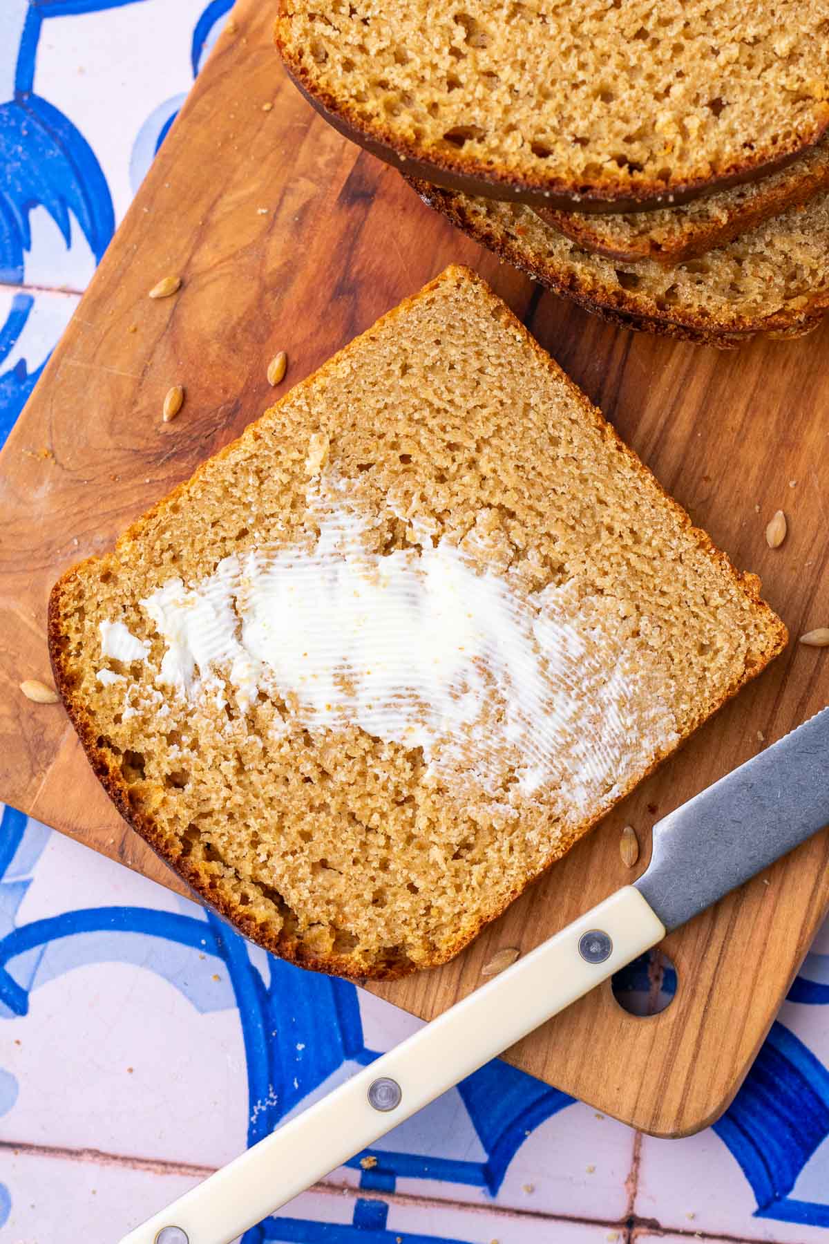 Slice of einkorn sourdough sandwich bread on a cutting board with butter and a knife.