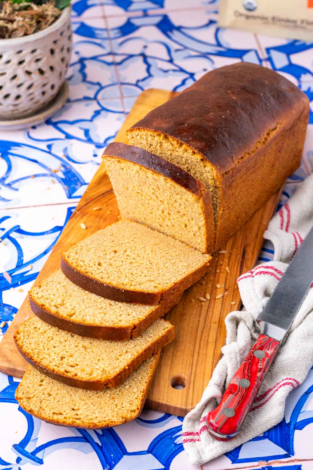 Sliced loaf of einkorn sourdough sandwich bread on a cutting board with a bread knife.