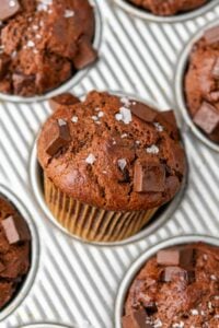 Sourdough chocolate muffin with chocolate chunks and flaky salt in a muffin pan.