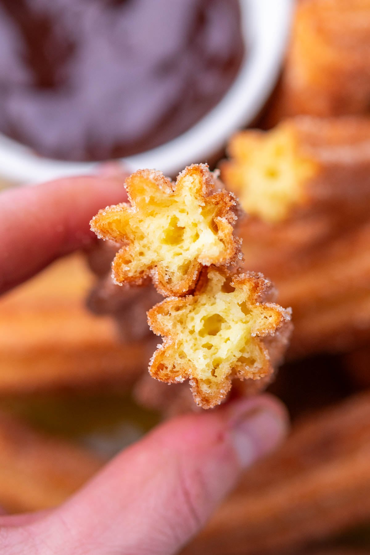 Hand holding the custard interior of crunchy sourdough churros.