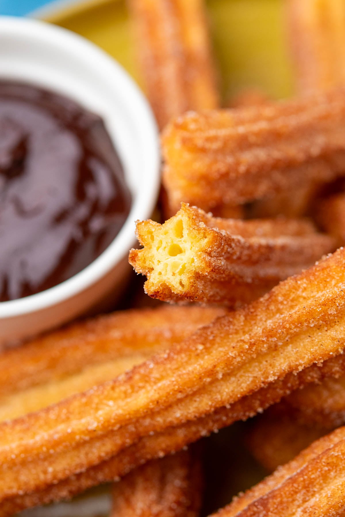 Custardy interior of sourdough churros with chocolate sauce in background.