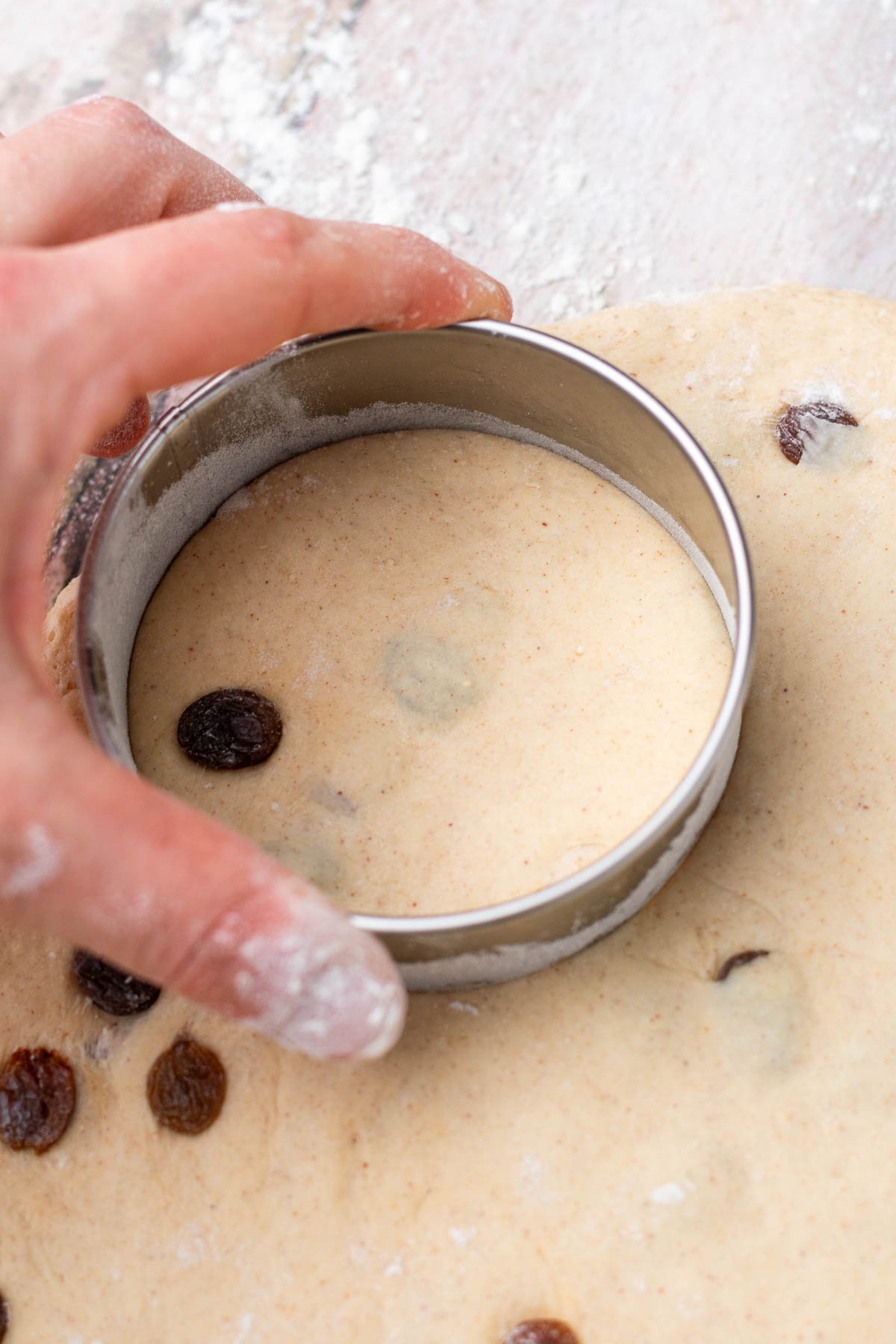 Cutting out sourdough cinnamon raisin english muffins with a cookie cutter.