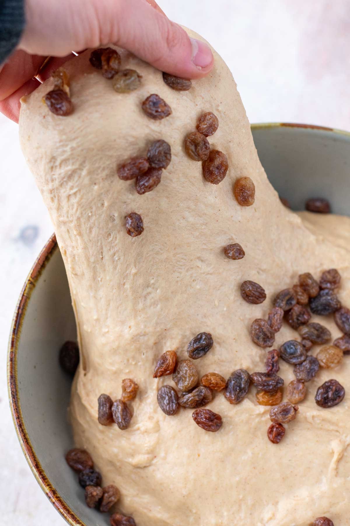 Hand stretching raisins into sourdough english muffin dough.