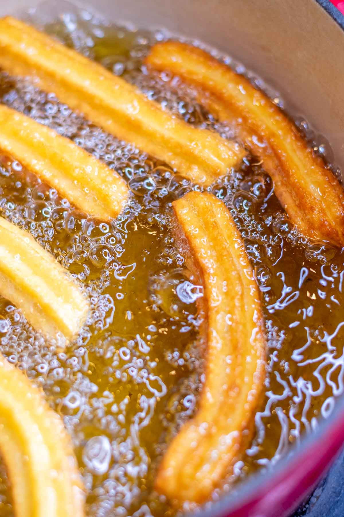 Frying sourdough churros in hot oil.