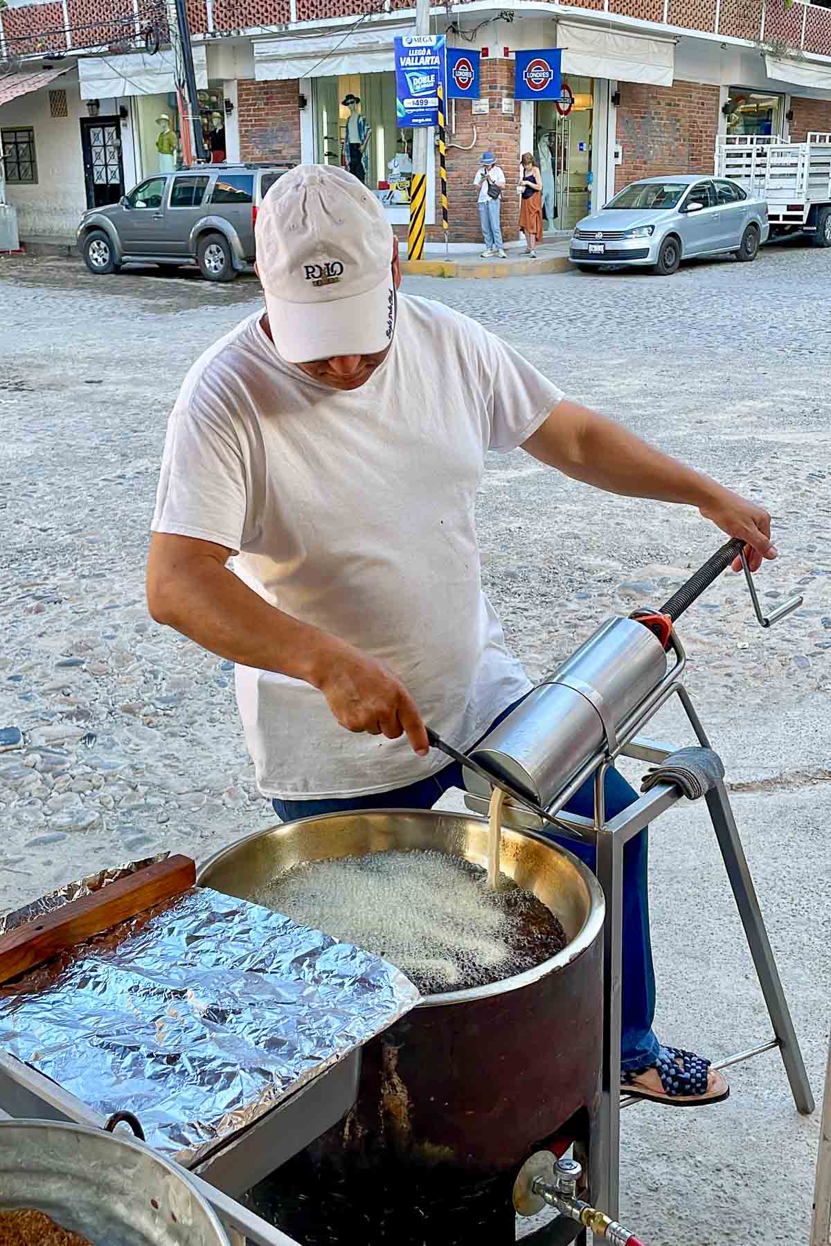 Man in mexico frying churros on the street.