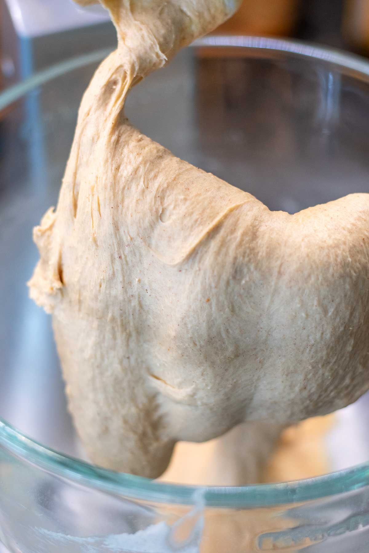 Mixed sourdough cinnamon raisin english muffin dough in a stand mixer with a dough hook.