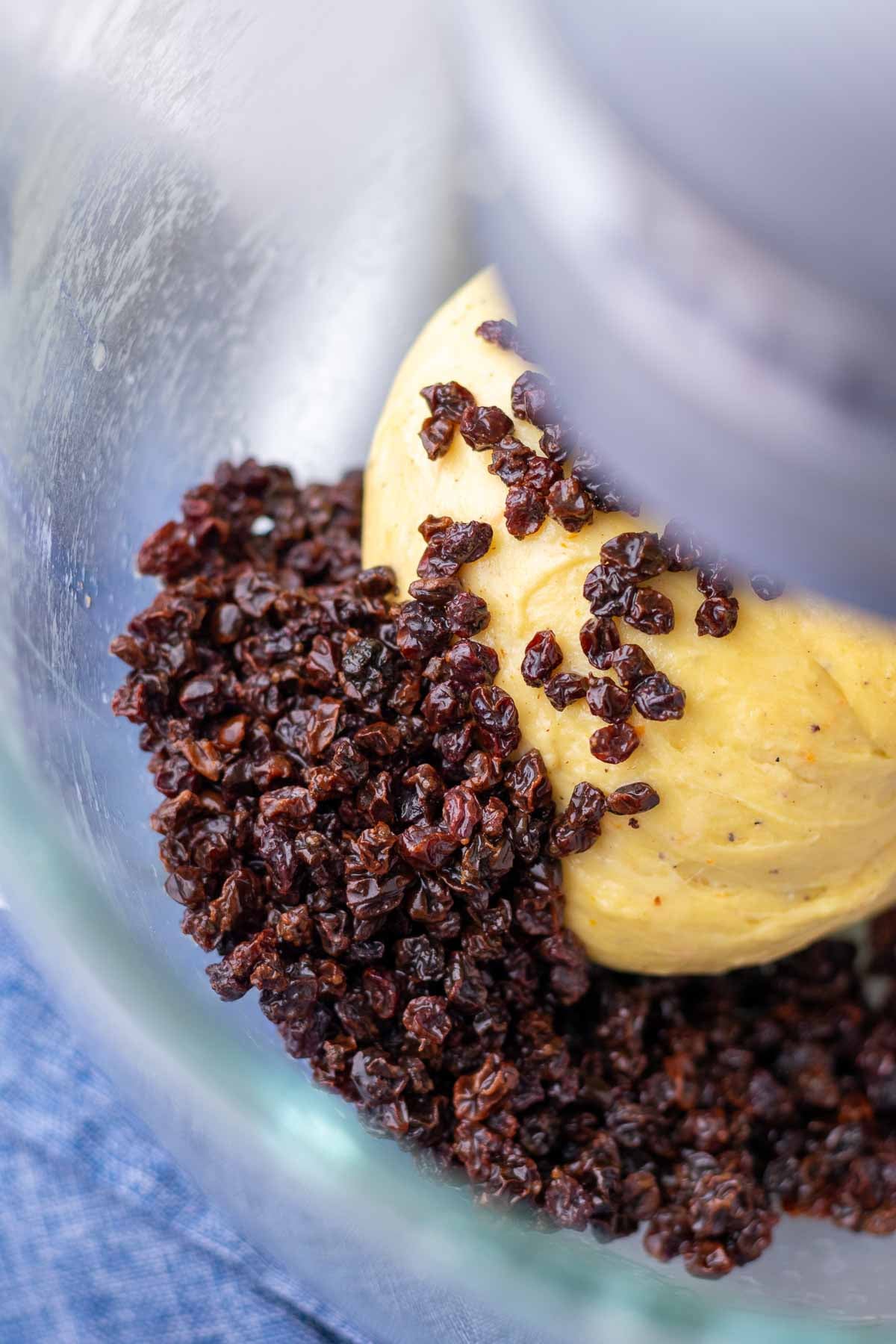 Currants added to sourdough hot cross bun dough in a stand mixer.