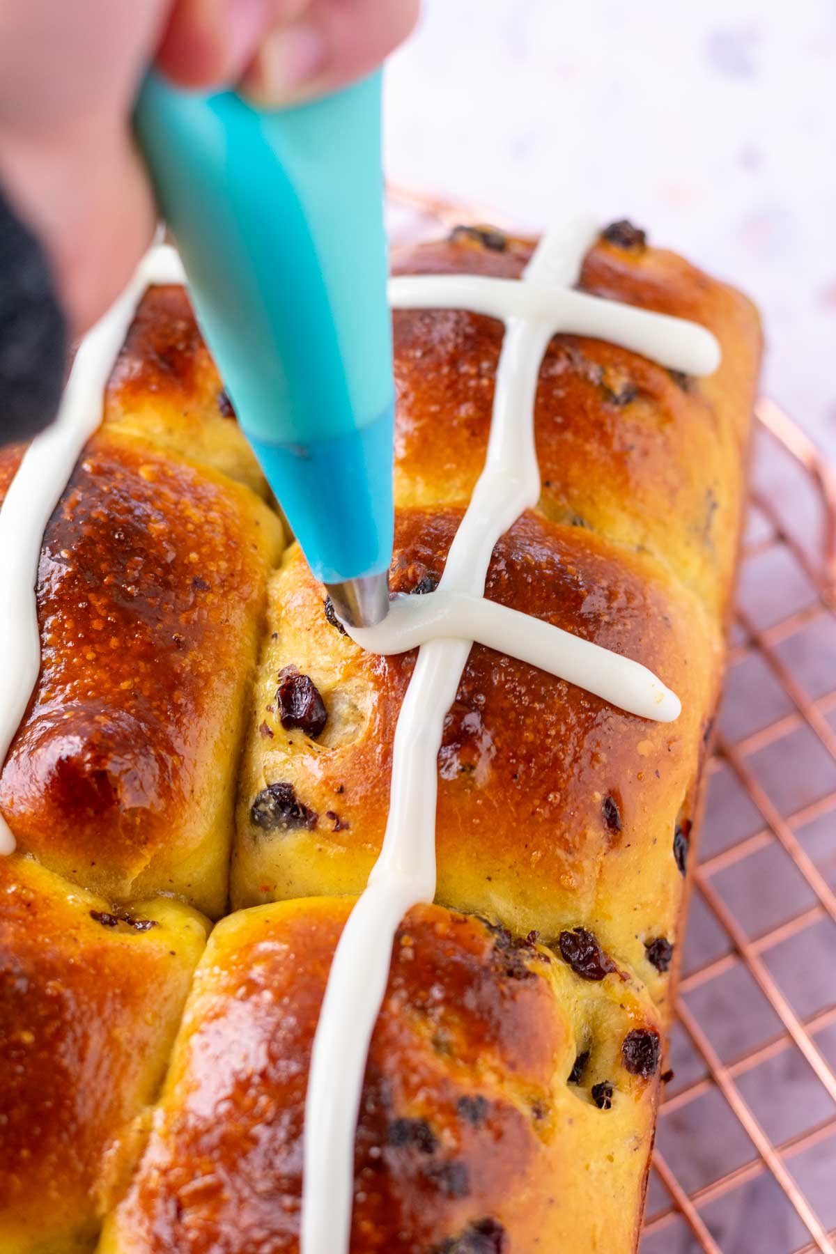 Piping icing onto sourdough hot cross buns.