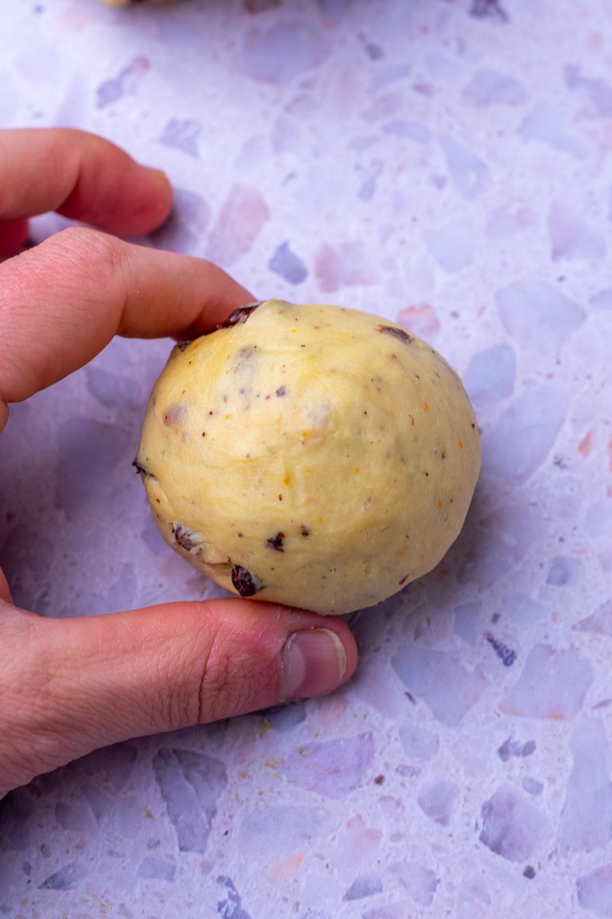 Hand shaping a sourdough hot cross bun.