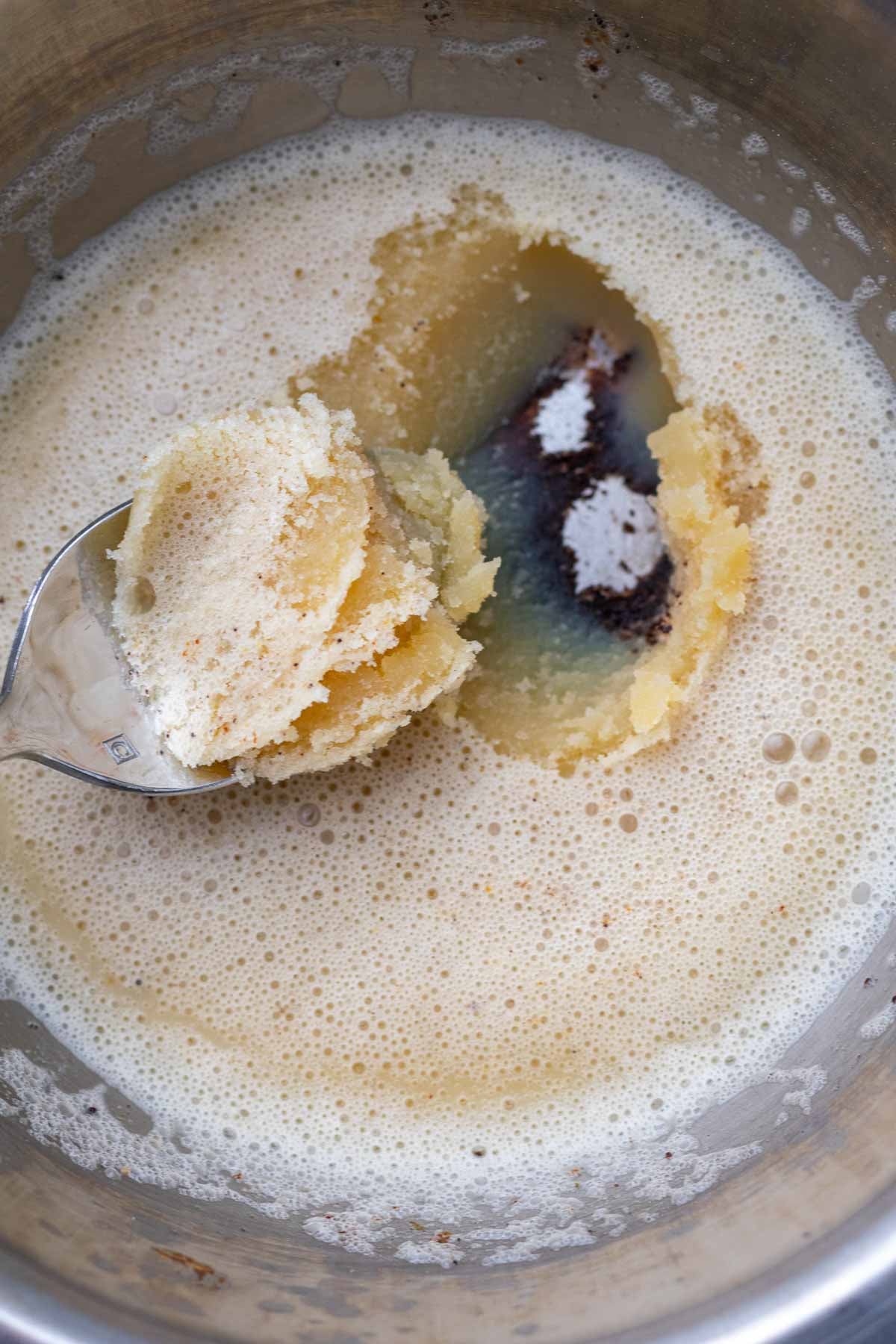 Spoon scooping cooled brown butter in a bowl.