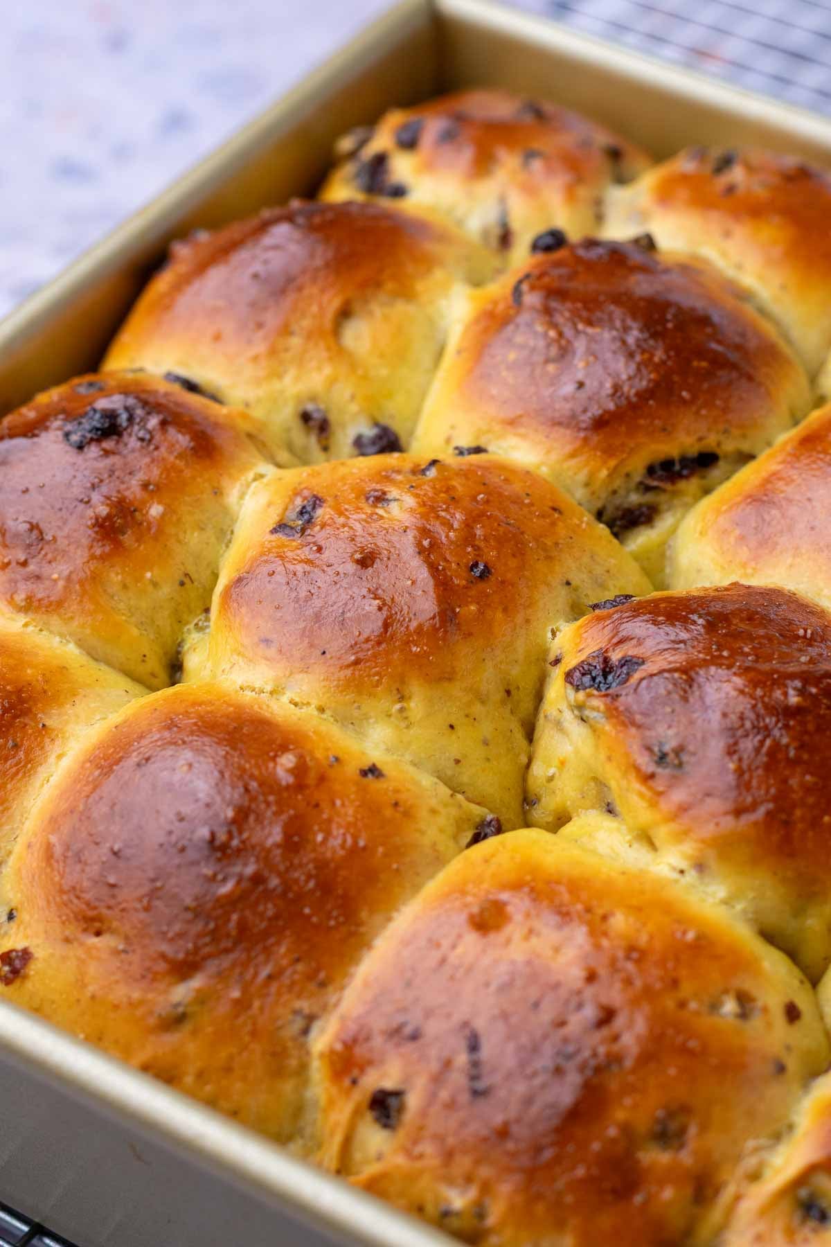 Baked sourdough hot cross buns in a pan.